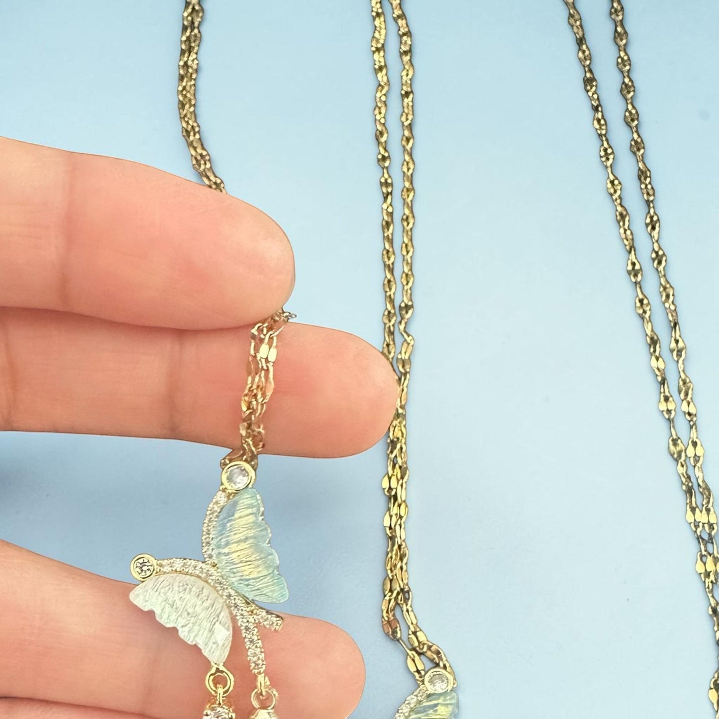 32lavender asymmetrical butterfly necklace with iridescent wings and cubic zirconia accents on a gold chain.